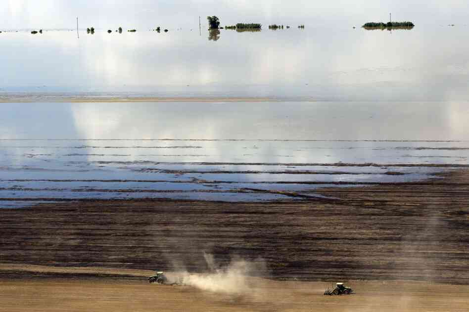 MAY 17: Floodwaters from the Mississippi river creep across the field as farmers work in Natchez, Miss. 