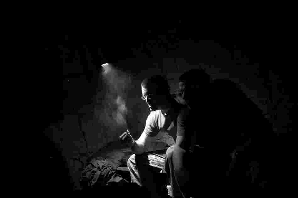 Marines wait for the mud and rain to stop falling after a massive dust and thunderstorm slams their base. The understanding is that while villagers are working in the fields, insurgents unplug IEDs (improvised explosive devices) and lie low.