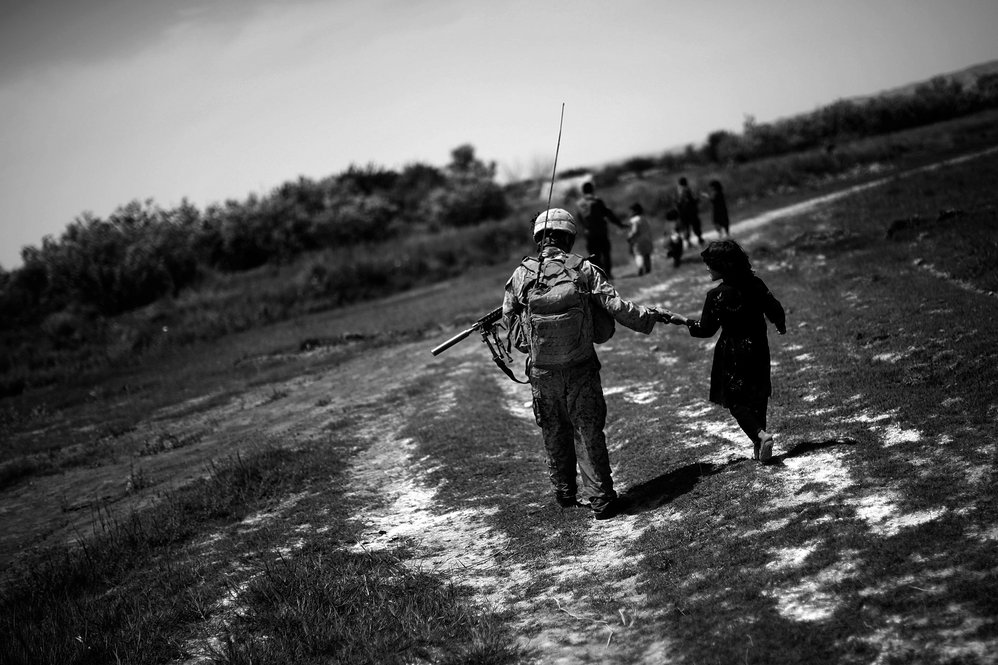 Lance Cpl. Victor Sierra holds the hand of an Afghan girl at the end of an all-day patrol in Sangin District.