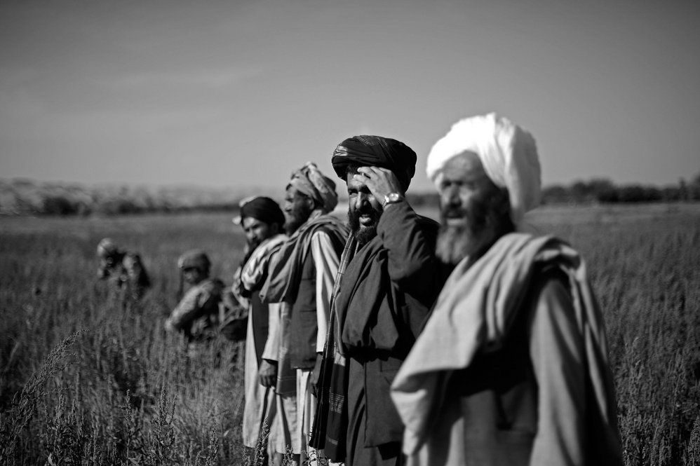 A group of Afghan farmers stand in the middle of a Marine patrol passing through the "green zone."