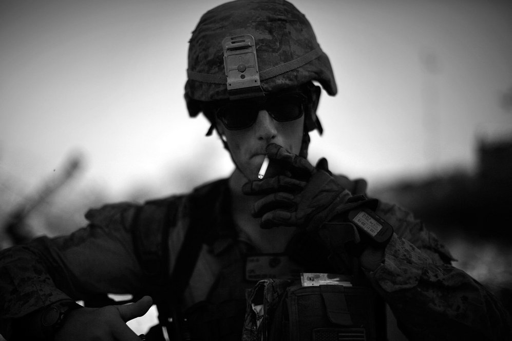 Cpl. Daniel Wheeler lights a cigarette after late afternoon patrol in the scorching heat. Some of the Marines have nicknamed the area "Vietnamistan," after the marshes and junglelike terrain that they navigate daily.
