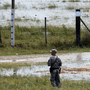 A member of the Louisiana National Guard stands guard as water diverted through the Morganza Spillway begins to fill a pasture in Morganza, La., on Saturday.