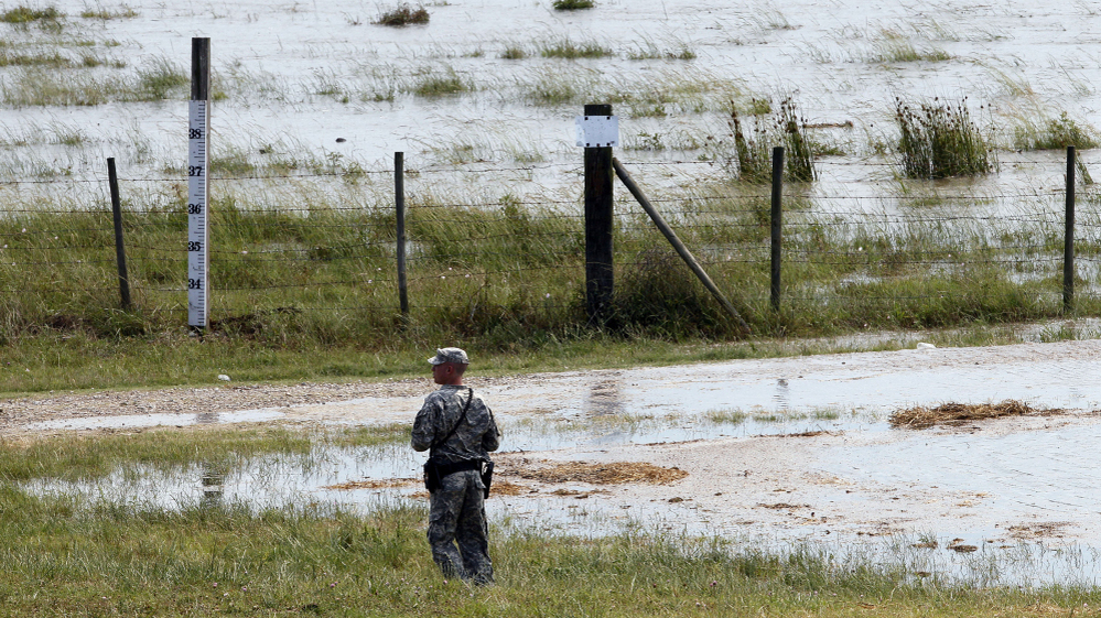 A member of the Louisiana National Guard stands guard as water diverted through the Morganza Spillway begins to fill a pasture in Morganza, La., on Saturday.