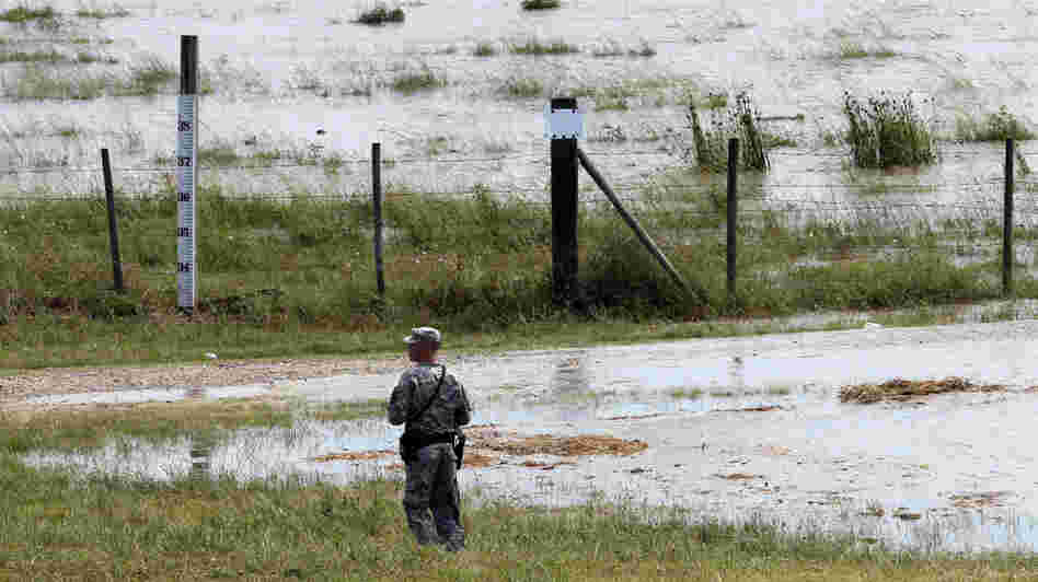 A member of the Louisiana National Guard stands guard as water diverted through the Morganza Spillway begins to fill a pasture in Morganza, La., on Saturday.