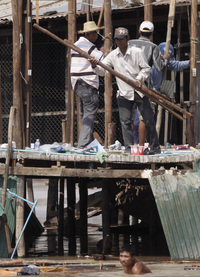 City workers in the Cambodian capital, Phnom Penh, demolish wooden houses in Boeung Kak Lake as a man in the water collects his belongings on Jan. 14.