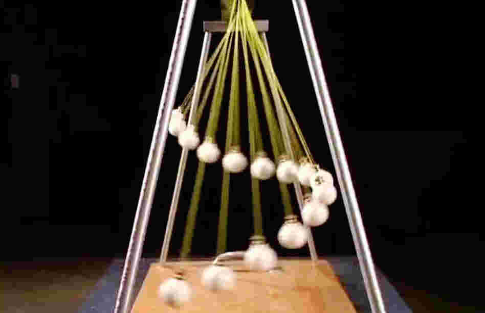 A still frame from a video of pendulums dancing together creating waves. A still frame from a video of pendulums dancing together creating waves.