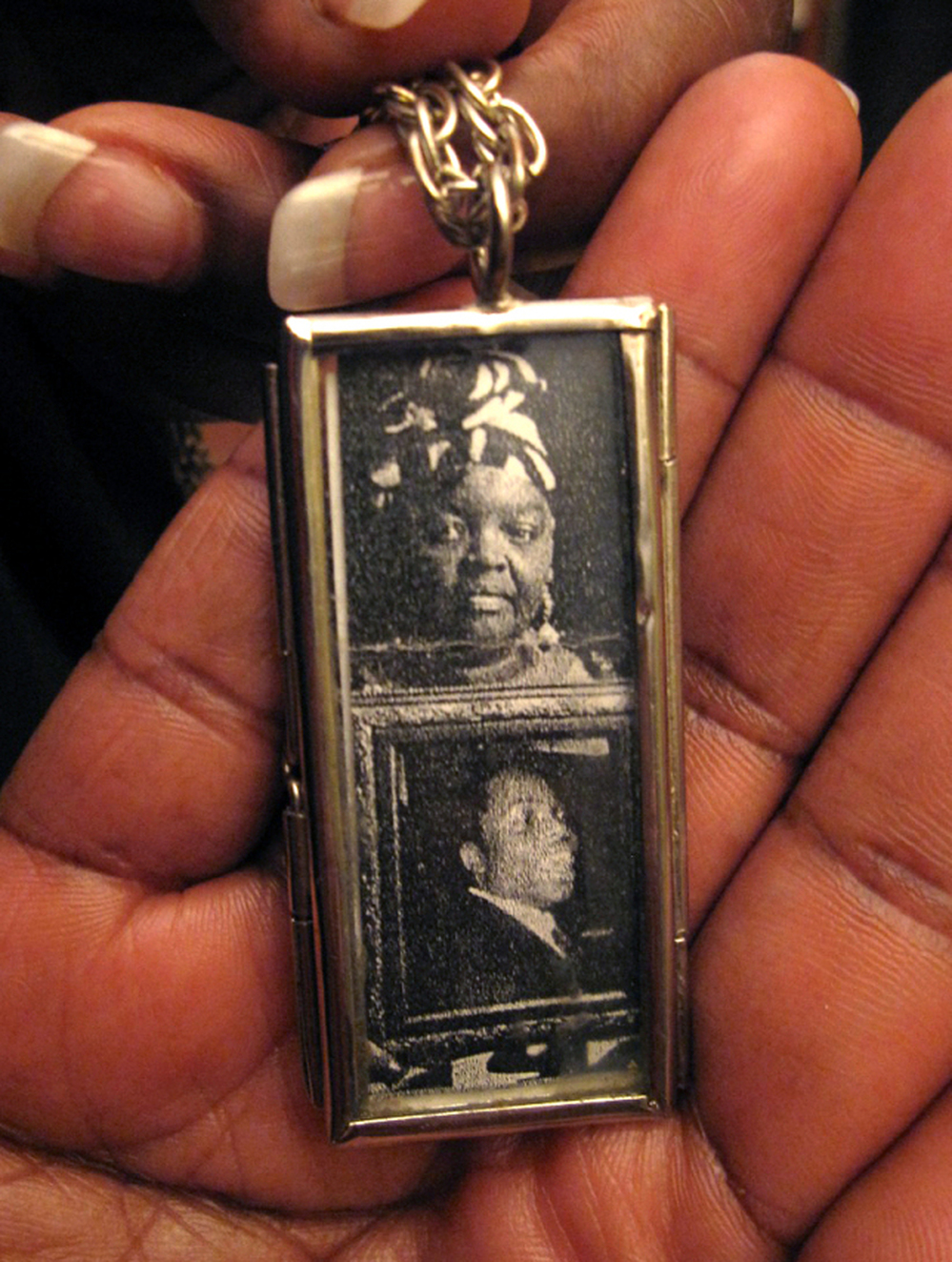 Mary Johnson holds a two-sided locket she wears on a necklace. On one side are photos of herself and her son; the other has a picture of Oshea Israel.