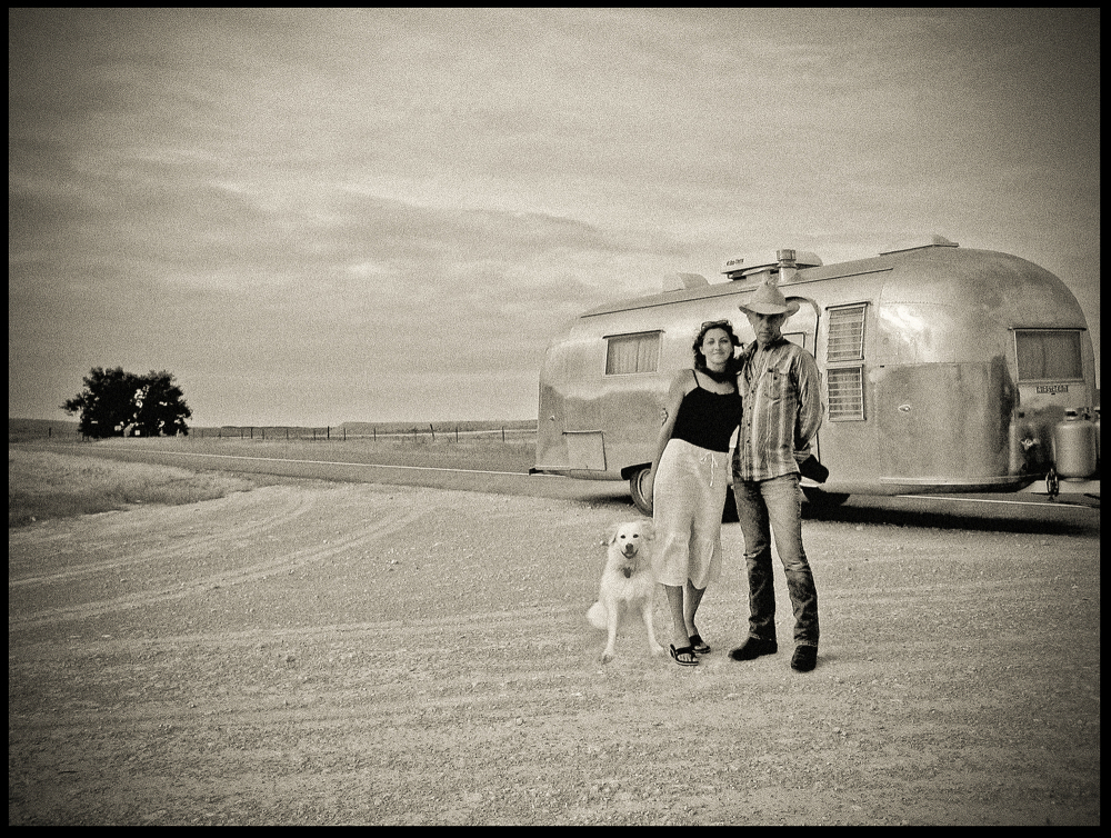 David Michael Kennedy with Heather Howard and Henry Crow Dog in front of their 1959 Airstream trailer.