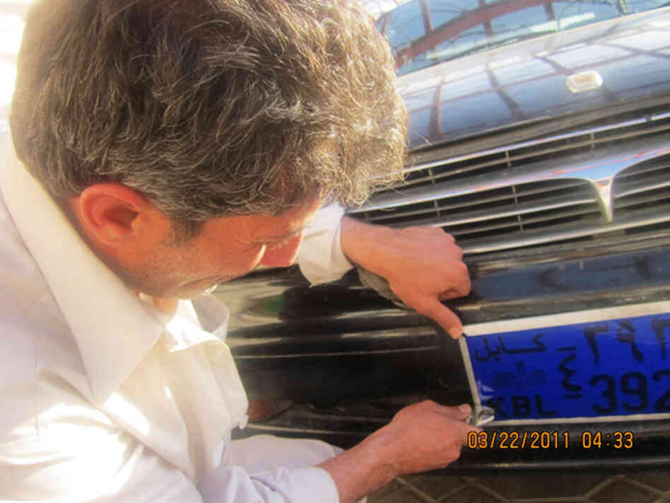 Waseh, an Afghan driver working for an international NGO, is trying to cover the license plate containing the number 39 with a blue plastic sheet. He is also 39 years old.