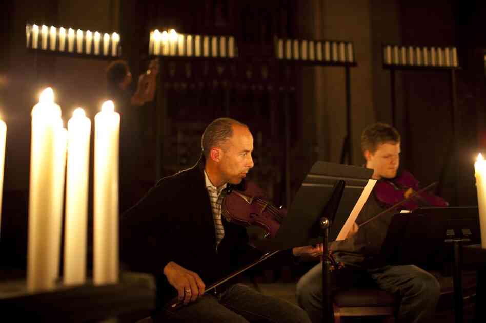 Musicians Greg Luce (left) and Stephen Redfield run through their music, as stagehands light candles in preparation for a dress rehearsal.