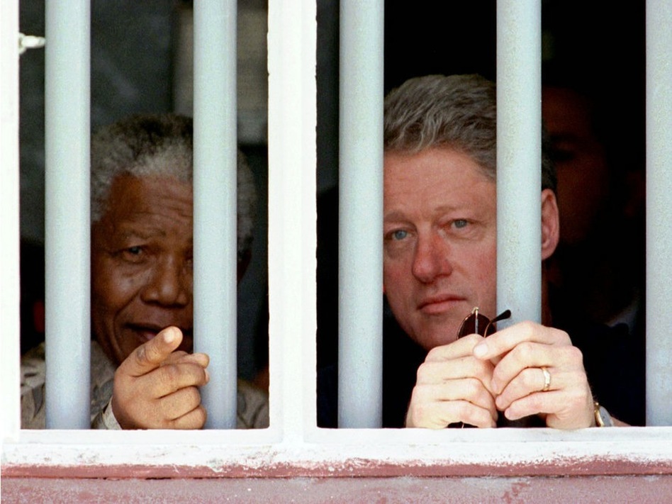 President Bill Clinton and Mandela peer through the bars of prison cell No. 5 on March 27, 1998. Mandela was jailed for 18 years in the cramped gray cell in his struggle against apartheid.