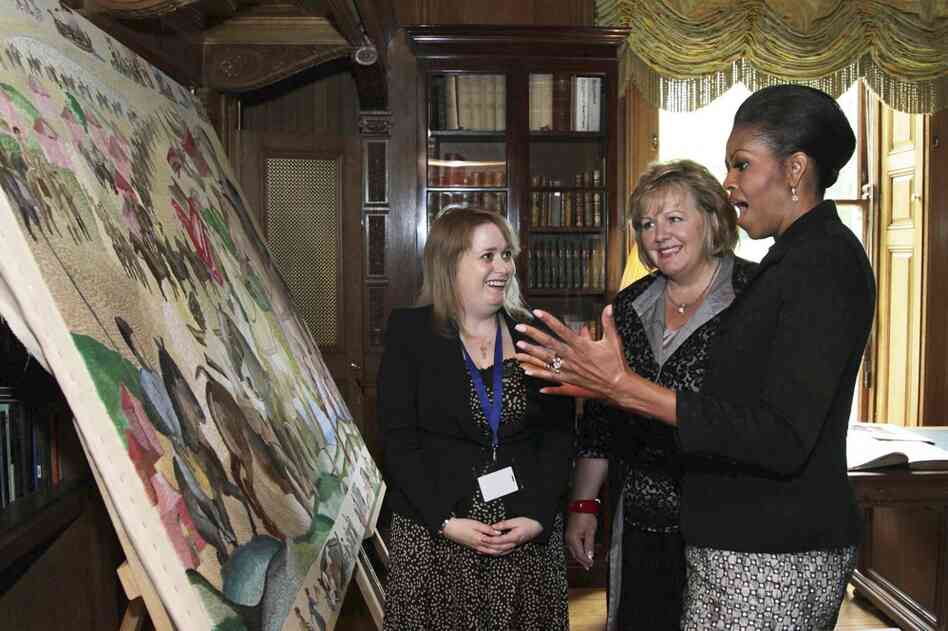 First lady Michelle Obama and Fionnuala Kenny (center), the wife of Irish Prime Minister Enda, view an embroidered panel depicting the Norman Invasion, during a tour of Farmleigh House in Dublin. 