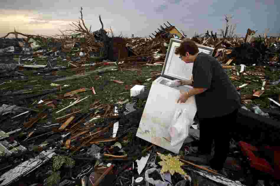 Anita Stokes salvages meat from a freezer where her home once stood in Joplin. 
