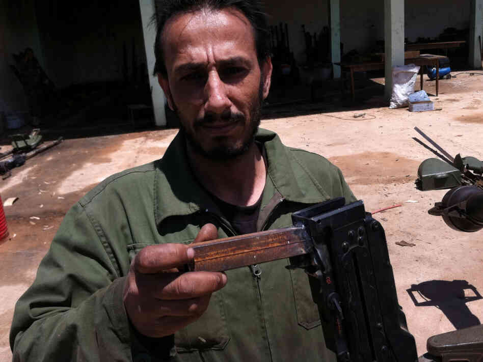 At the rebels' outdoor machine shop, they rehabilitate antique automatic weapons and sometimes redesign them.  Saleh Likhfayfe shows off the new "grip" welded onto a salvaged machine gun.