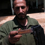 At the rebels' outdoor machine shop, they rehabilitate antique automatic weapons and sometimes redesign them.  Saleh Likhfayfe shows off the new "grip" welded onto a salvaged machine gun.