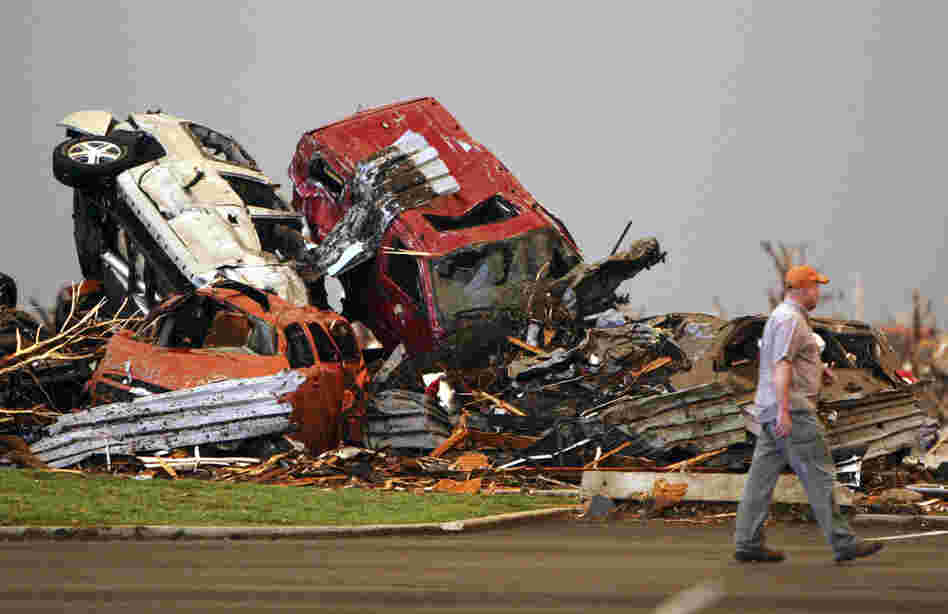 A man walks past destroyed vehicles in the parking lot of St. John's Regional Medical Center. 