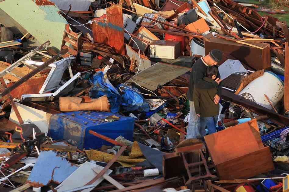Ernie Darby hugs his son amid the rubble of their destroyed house.  