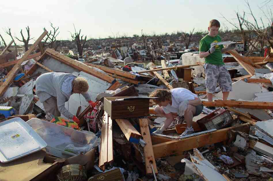 Beverly Winans (left), Debbie Spurlin and Austin Spurlin shift through belongings from their home. 