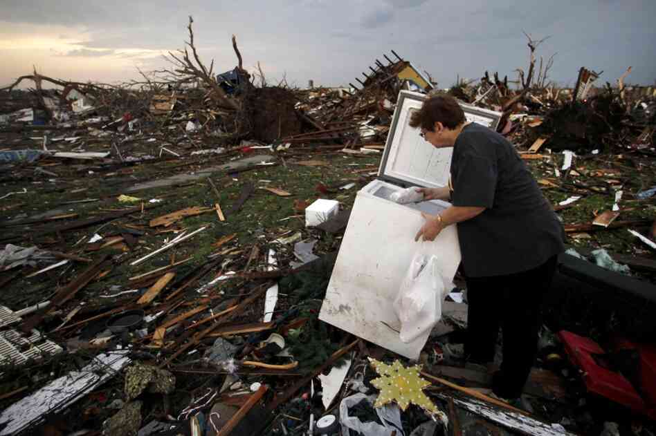 Anita Stokes salvages meat from a freezer where her home once stood in Joplin. 