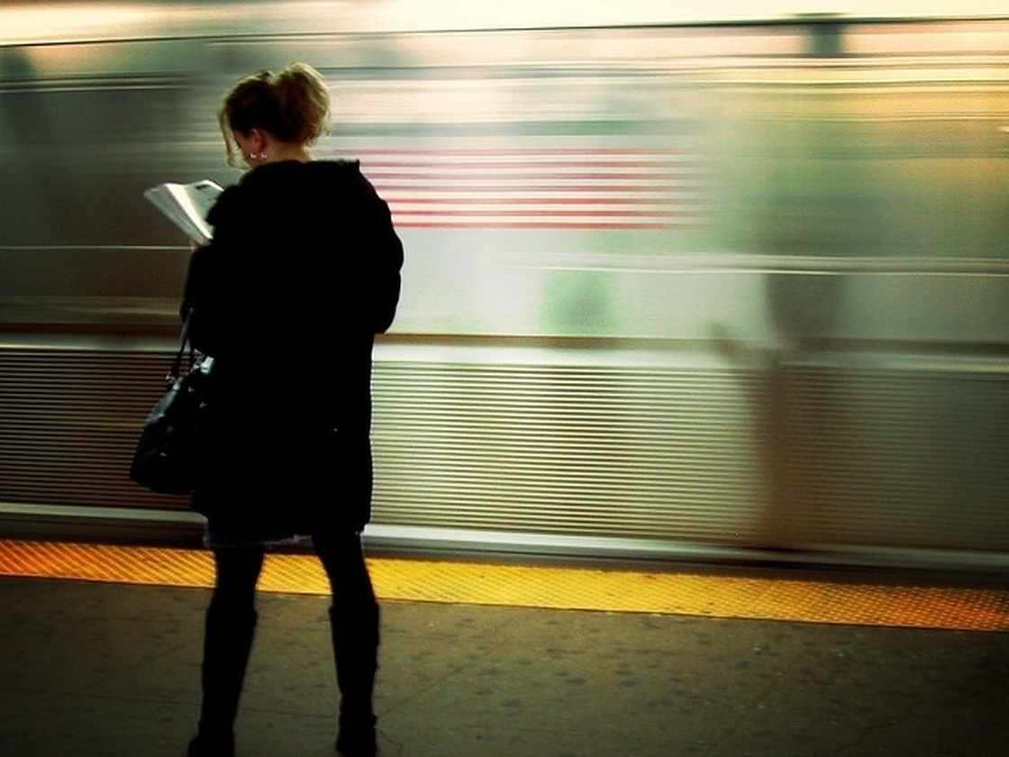 A commuter reads while as her train arrives.