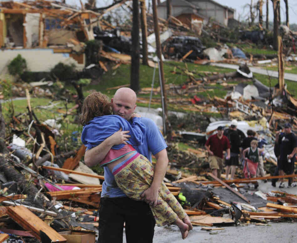 A man carries a young girl who was rescued after being trapped with her mother in their home after a tornado hit Joplin. 