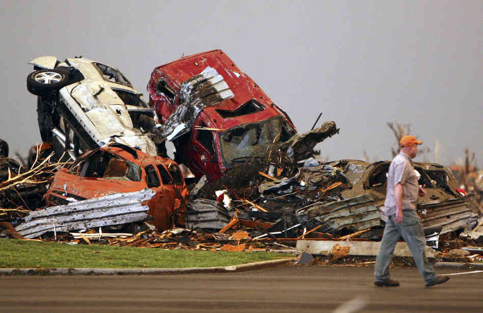 A man walks past destroyed vehicles in the parking lot of St. John's Regional Medical Center. 