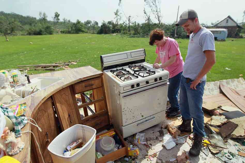 Elizabeth Vandenberg  and Paul Garnec stand in what remains of her living room as she salvages what she can from her trailer in Denning, Ark. 