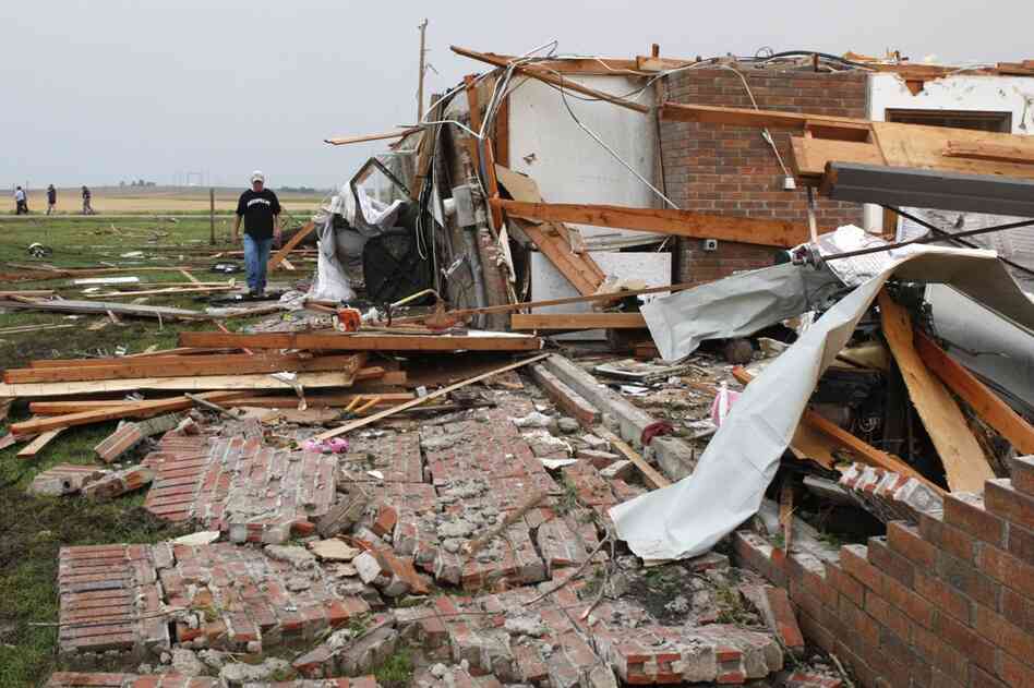 Matt McElvany walks past the home of a friend in Piedmont, Okla., following a tornado on Tuesday. 