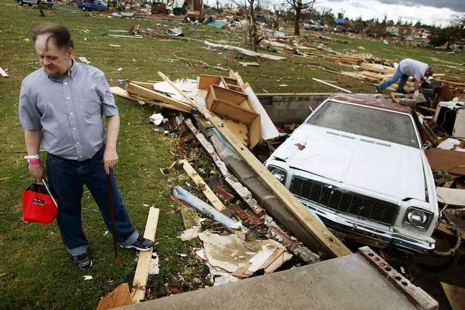 Steve Goebel (left) stands outside the crawlspace of his destroyed home after a massive tornado passed through Duquesne, Mo. Gobel was trapped for hours after cars were blown over the crawlspace. 