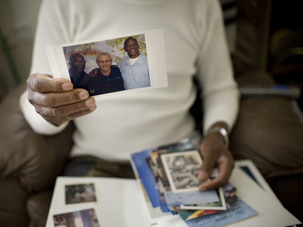Robert Dixon Sr. holds a photograph of his son, Robert Dixon Jr. (far right), his son's mentor Bob Stuart, and himself (far left).