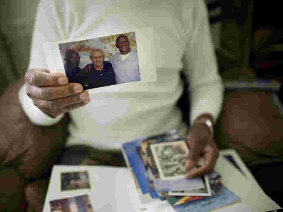 Robert Dixon Sr. holds a photograph of his son, Robert Dixon Jr. (far right), his son's mentor Bob Stuart, and himself (far left).