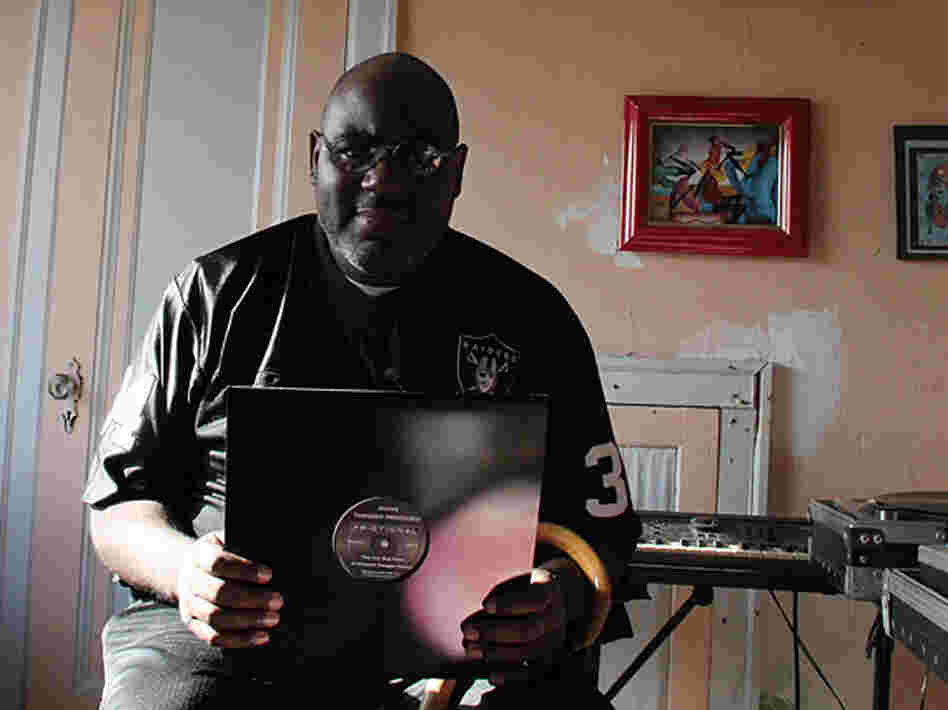 Anthony "Shake" Shakir in his home, holding up one of his records.