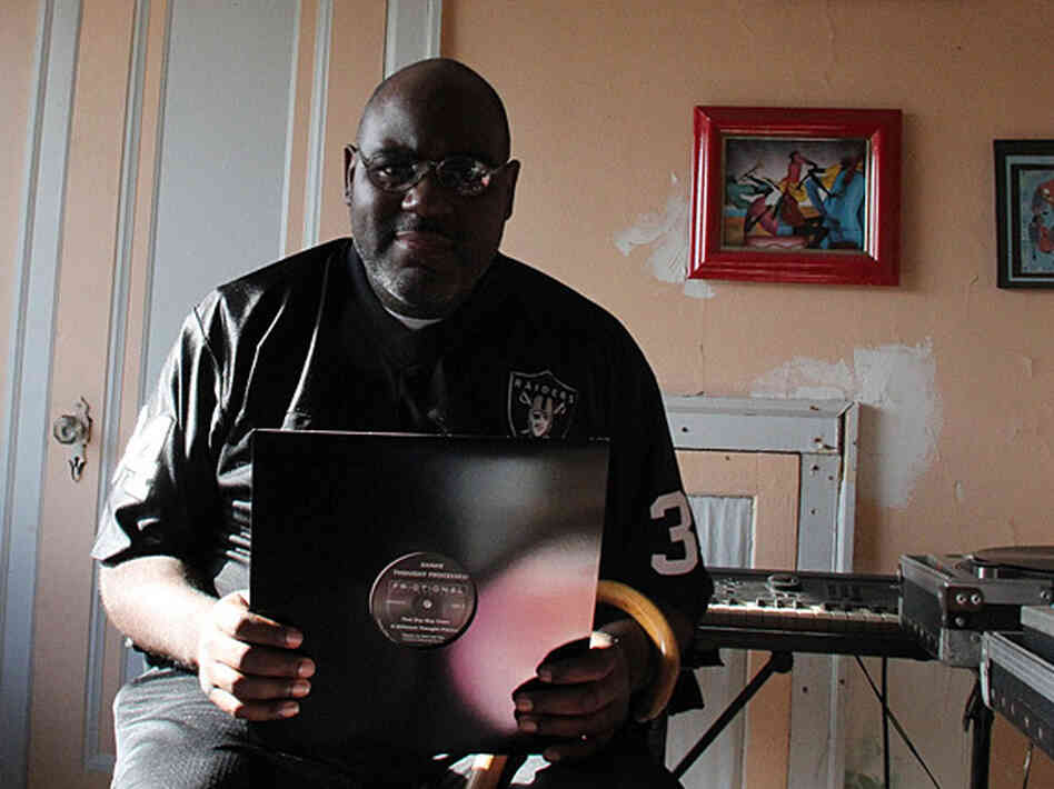 Anthony "Shake" Shakir in his home, holding up one of his records.