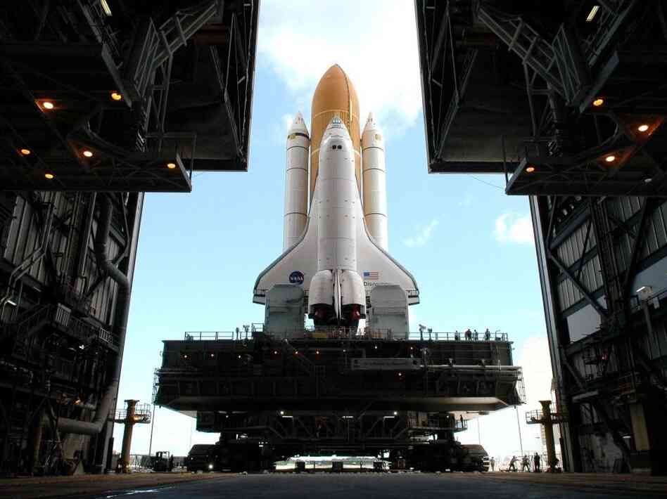 Framed in the doors of the Kennedy Center's Vehicle Assembly Building, the crawler begins the long journey toward Launch Pad 37B with space shuttle Discovery in April 2005.  This enormous cross between a tank and a cargo ship is the largest self-powered land vehicle in the world.