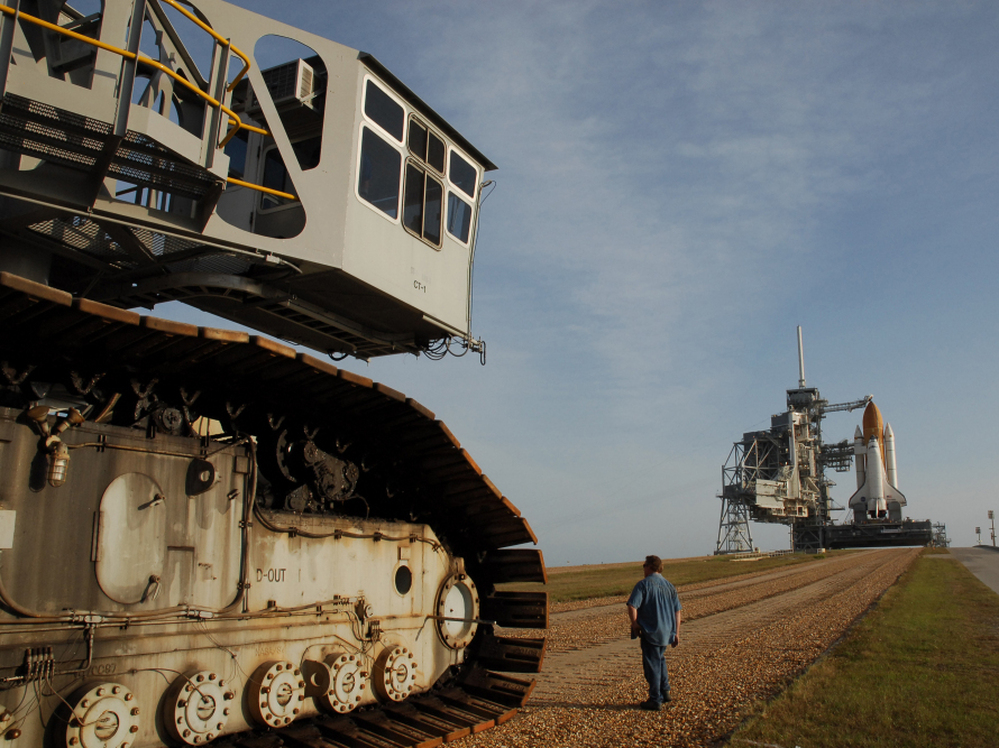 The crawler's titanic treads grip the dirt of the "crawlerway," a special road between the launchpad and the hangar-like structure where the shuttle is assembled.  The road is designed to hold the combined 18 million pounds of the crawler and the shuttle it carries.