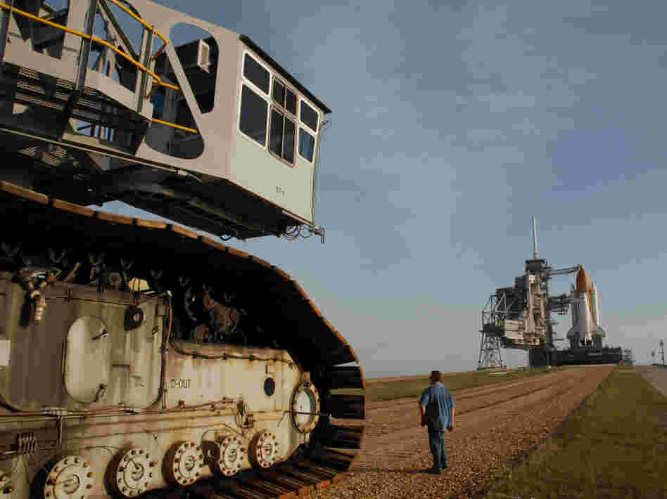 The crawler's titanic treads grip the dirt of the "crawlerway," a special road between the launchpad and the hangar-like structure where the shuttle is assembled.  The road is designed to hold the combined 18 million pounds of the crawler and the shuttle it carries.