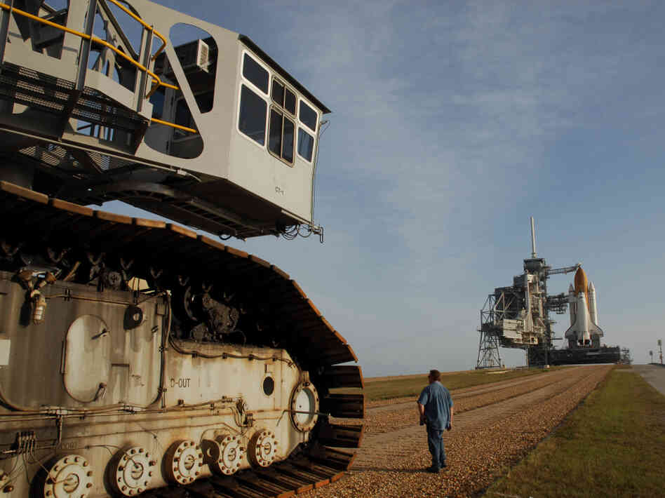 The crawler's titanic treads grip the dirt of the "crawlerway," a special road between the launchpad and the hangar-like structure where the shuttle is assembled.  The road is designed to hold the combined 18 million pounds of the crawler and the shuttle it carries.