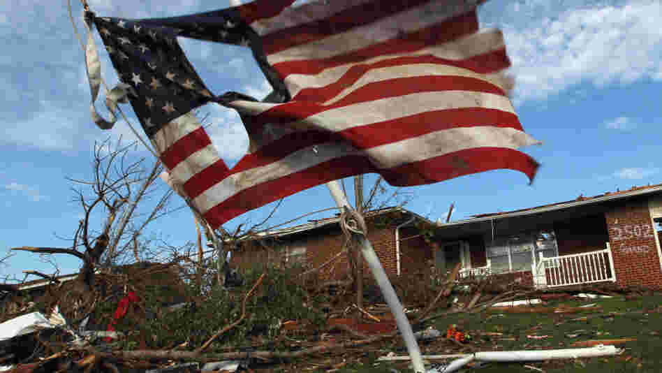 A torn U.S. flag hangs outside a house damaged during Sunday's massive tornado in Joplin, Mo. As of Thursday, local police said they had arrested 16 people for looting and burglary and four for assault since the twister hit.