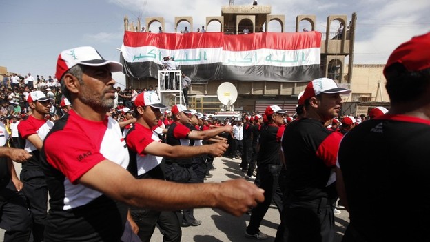 Supporters of cleric Muqtada al-Sadr march in front of two large Iraqi flags with the Arabic words "God is great," in the Sadr City district of Baghdad on Thursday. Tens of thousands of Sadr's followers rallied to demand the U.S. military leave Iraq at the end   of the year.