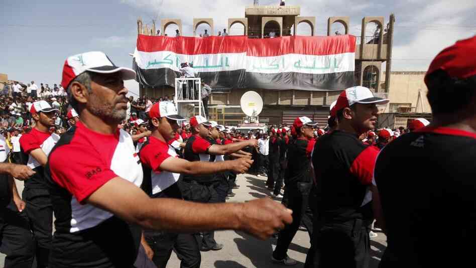 Supporters of cleric Muqtada al-Sadr march in front of two large Iraqi flags with the Arabic words "God is great," in the Sadr City district of Baghdad on Thursday. Tens of thousands of Sadr's followers rallied to demand the U.S. military leave Iraq at the end   of the year.