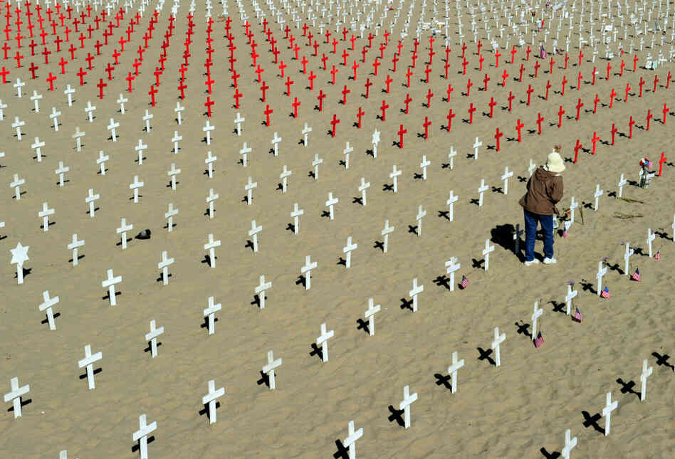A woman walks among crosses at the Arlington West Memorial in Santa Monica, Calif., on Monday. Each red cross stands for 10 lost lives — a sign of the rising toll from the wars in Afghanistan and Iraq. A woman walks among crosses at the Arlington West Memorial in Santa Monica, Calif., on Monday. Each red cross stands for 10 lost lives — a sign of the rising toll from the wars in Afghanistan and Iraq.