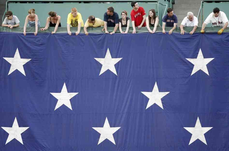 Boston Red Sox fans hold a large American flag before a game on Monday.