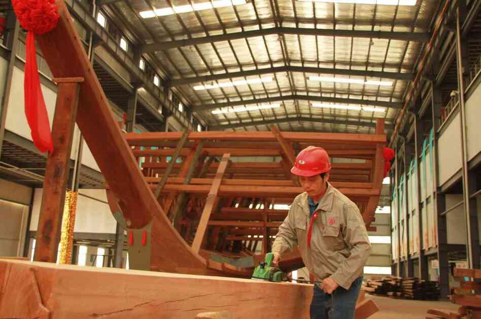 A worker in Nanjing planes a beam for a replica of one of Zheng He's treasure ships, which the explorer sailed in the 1400s.
