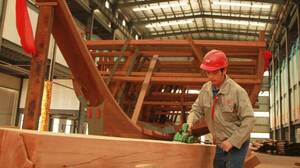 A worker in Nanjing planes a beam for a replica of one of Zheng He's treasure ships, which the explorer sailed in the 1400s.