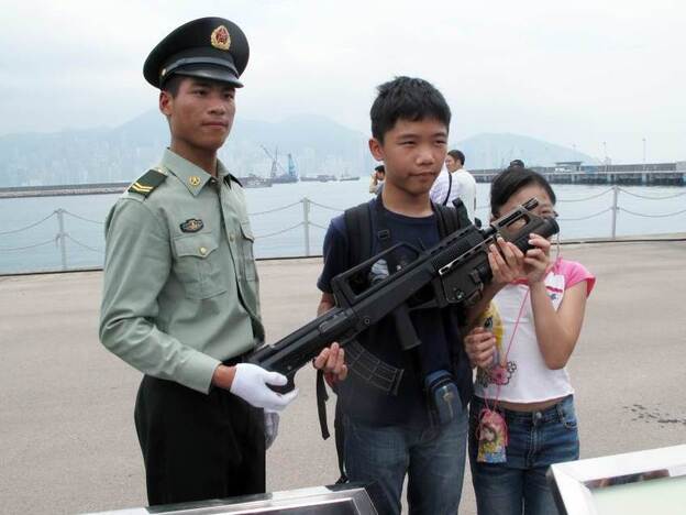 China's army bases open their doors every year to try to build their image among Hong Kong's population. Troops pose for pictures and allow children to learn about their weapons.