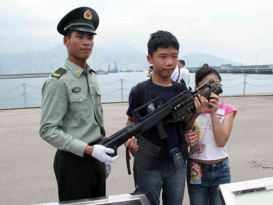 China's army bases open their doors every year to try to build their image among Hong Kong's population. Troops pose for pictures and allow children to learn about their weapons.