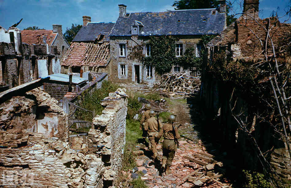 Soldiers search ruined homes in western France after D-Day.