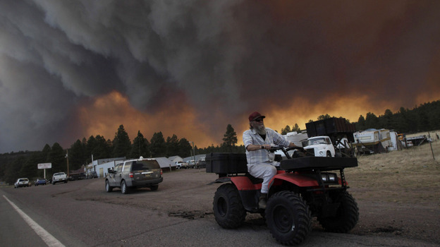 Robert Joseph, 64, rides his ATV as smoke plumes from the Wallow Fire fill the sky in Luna, N.M., on Monday.