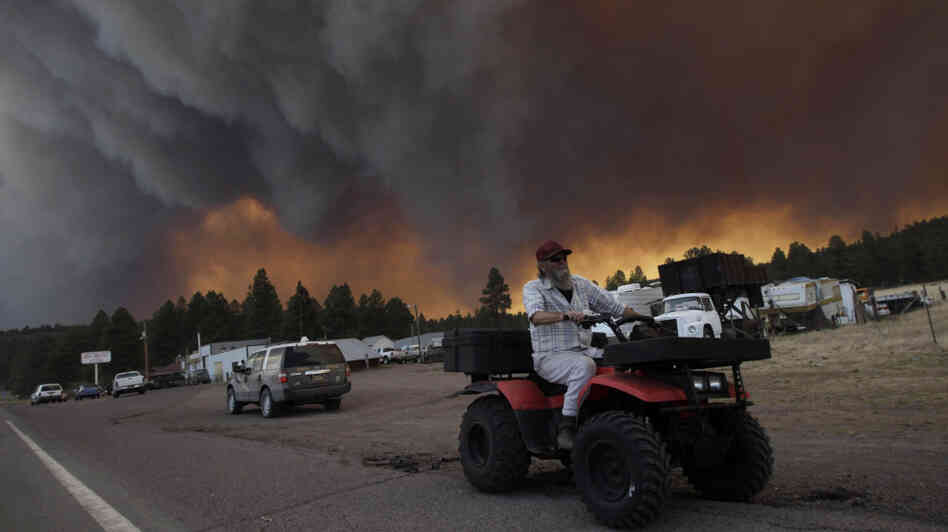 Robert Joseph, 64, rides his ATV as smoke plumes from the Wallow Fire fill the sky in Luna, N.M., on Monday.