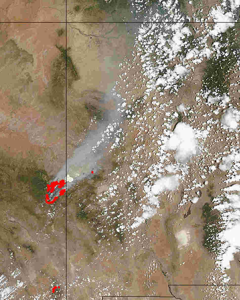 This satellite image from NASA's MODIS Land Rapid Response Team shows the fires in red, along the Arizona border with New Mexico (the line just to the right of the red marks that pinpoint the flames), and the smoke billowing to the northeast. It was taken Monday.